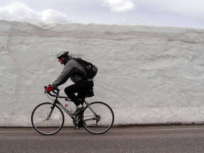 A bicyclist rides past freshly plowed snow along the road between Norris and Canyon Village in this 2012 file photo.