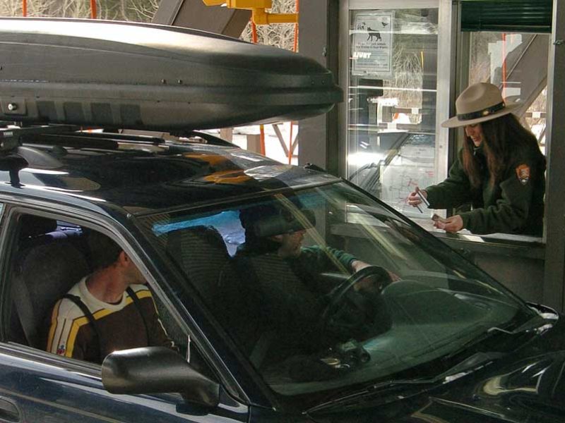 Candice Phipps, a worker at the East Gate to Yellowstone National Park, checks passes of visitors arriving from Cody in this 2012 file photo.