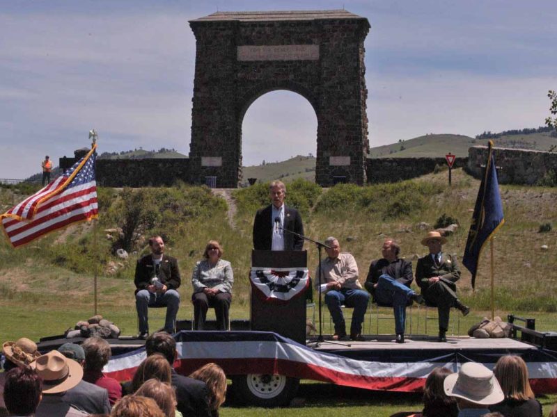 Bill Berg, president of the Greater Gardiner Community Council, speaks in front of the Roosevelt Arch during the Gardiner Gateway Project kickoff event Thursday. Joining him on stage were, from left, Daniel Bierschwale, President, Gardiner Chamber of Commerce; Clara Conner, Division Engineer, Western Federal Lands Highway Division; Marty Malone, Commissioner, Park County, Mont.; Brian Schweitzer, Governor of Montana; and Dan Wenk, Superintenden of Yellowstone National Park. (Ruffin Prevost/Yellowstone Gate - click to enlarge)