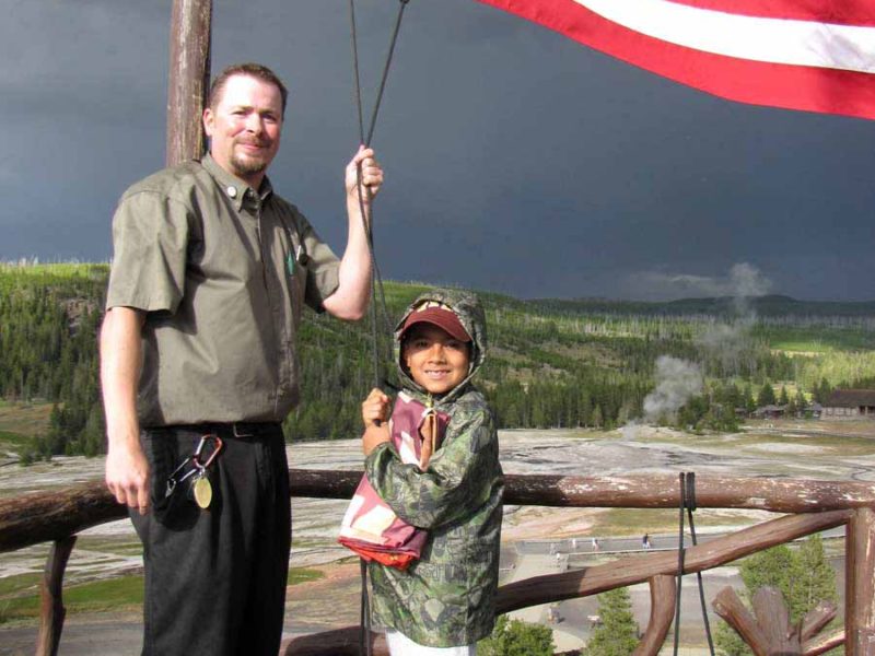 Nathan Bartlett, 8, helps Old Faithful Inn bellman Ed Nabors take down the American flag atop the hotel during a 2012 summer trip to Yellowstone National Park. (NPS photo by Dan Hottle - click to enlarge)