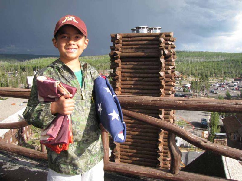 Nathan Bartlett, 8, holds two flags given to him by Xanterra Parks & Resorts atop the Old Faithful Inn in Yellowstone National Park. (NPS photo by Dan Hottle - click to enlarge)