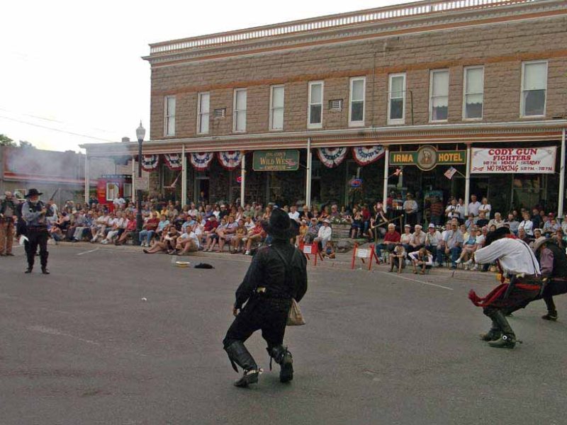 A crowd watches from the porch of the Irma Hotel in Cody as three villains are shot in a mock gunfight. (Ruffin Prevost - Yellowstone Gate file photo - click to enlarge)