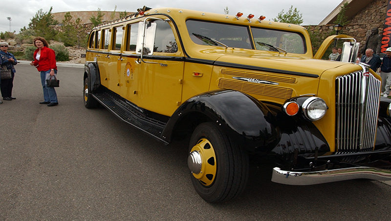 Park County Travel Council Marketing Director Claudia Wade, right, chats with visitors to the Buffalo Bill Historical Center in Cody, Wyo. about a refurbished 1936 tour bus that is used for commercial tours in Yellowstone National Park. (Yellowstone Gate file photo/Ruffin Prevost)