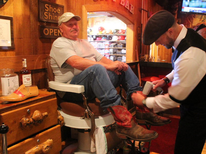 Tim Tetley works on Gordon Little’s boots at Tetley’s shoe-shine stand in the Cowboy Bar in Jackson, Wyo., south of Grand Teton National Park.