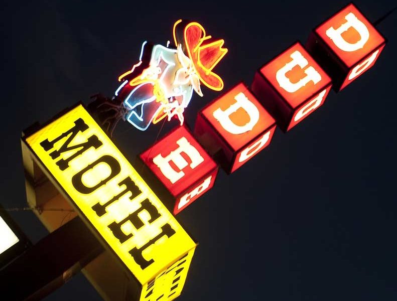 The Dude Motel sign lights up the night sky in West Yellowstone, Mont., where tourism has dropped sharply since the government shutdown closed Yellowstone National Park.