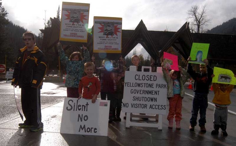 A group of kids hold up protest signs Sunday at the East Gate to Yellowstone National Park.