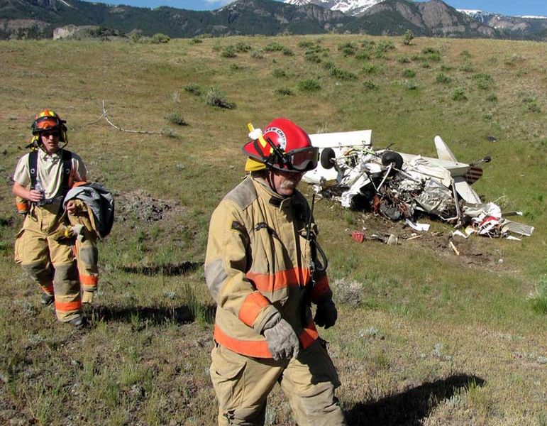 Emergency personnel walk past the wreckage of a crashed airplane Monday after the injured pilot was transported for medical care.