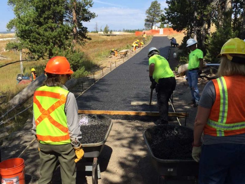 Volunteers help resurface a walking path near Old Faithful geyser in Yellowstone National Park.