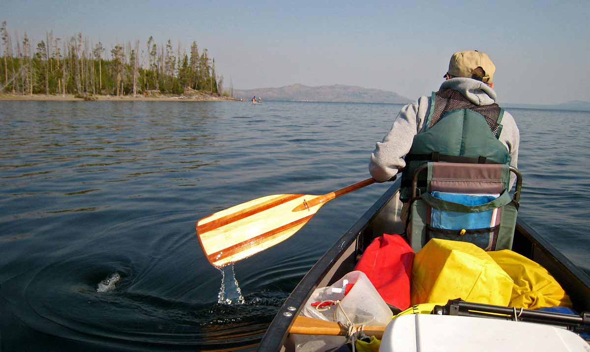 A canoeist paddles along the southeast arm of Yellowstone Lake in Yellowstone National Park.