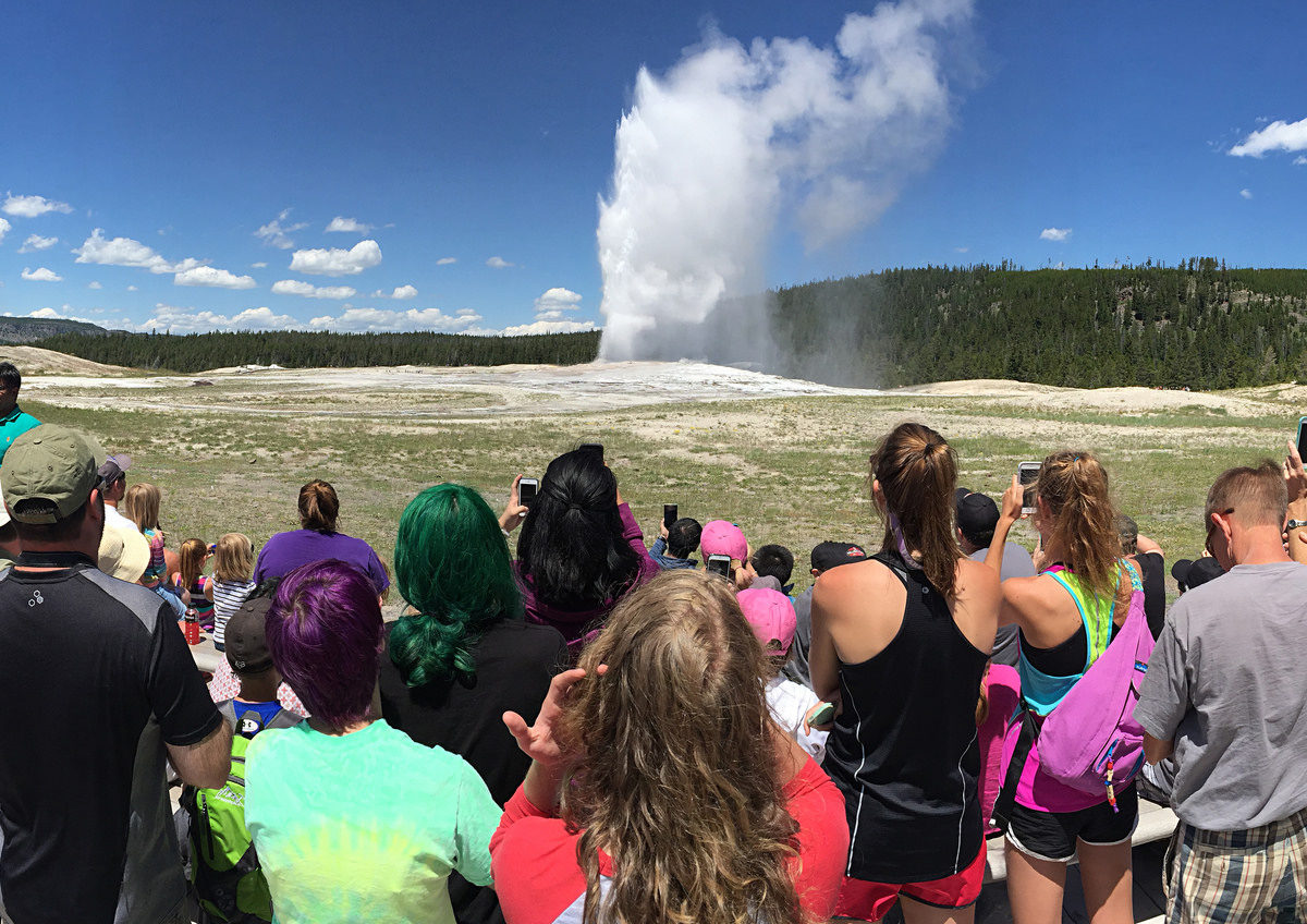 Visitors watch Old Faithful geyser erupt in Yellowstone National Park.